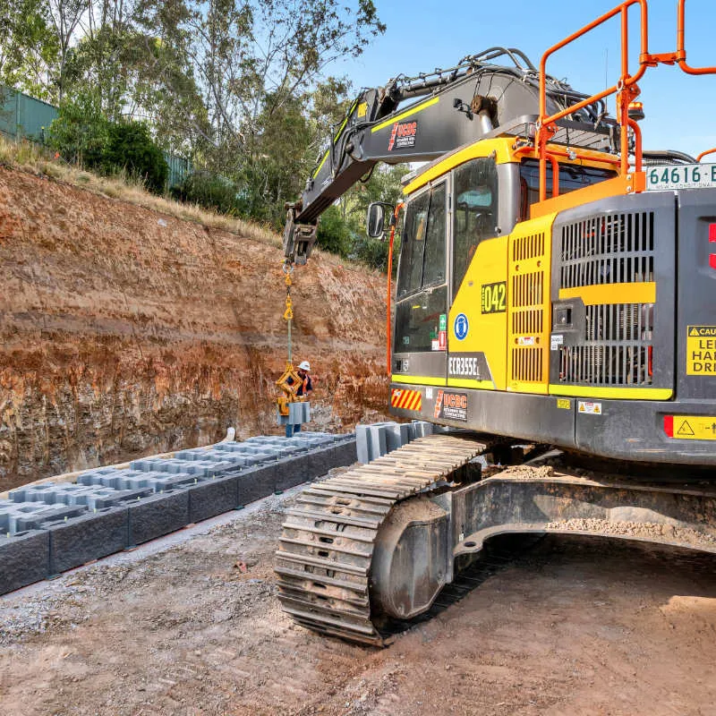 UCBC excavator and operator placing precast retaining wall units
