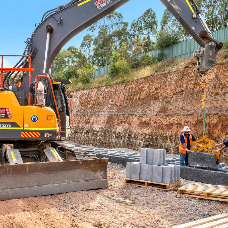 UCBC excavator and operator placing precast retaining wall units