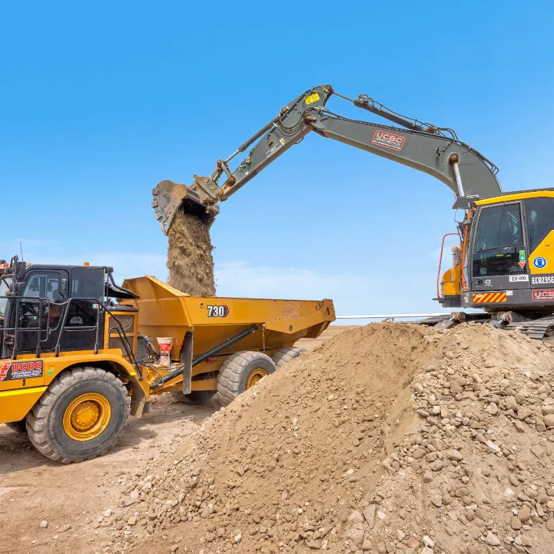 UCBC excavator and operator placing precast retaining wall units