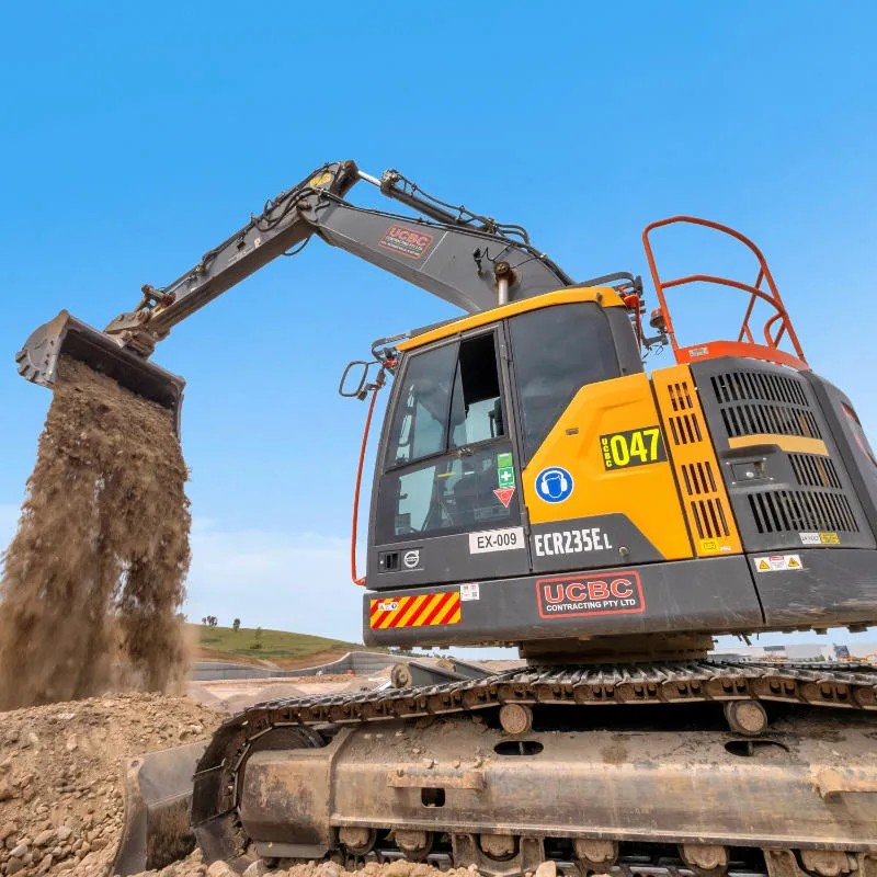 UCBC excavator and operator placing precast retaining wall units