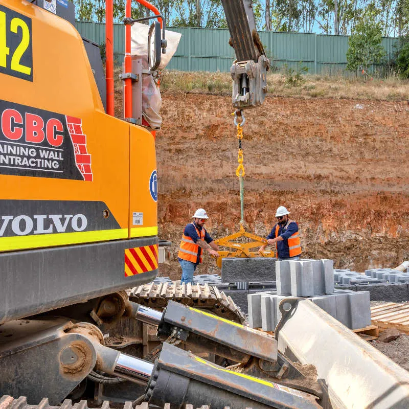 UCBC excavator and operator placing precast retaining wall units