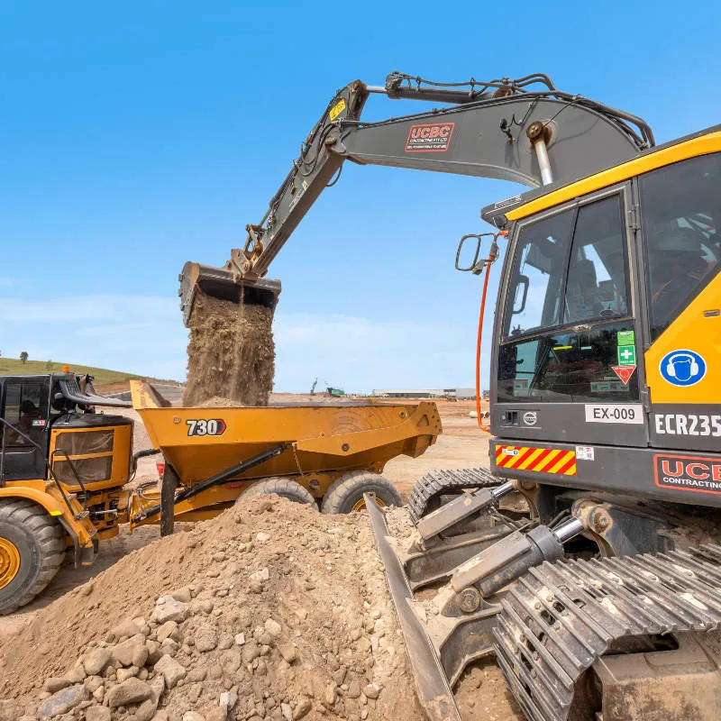 UCBC excavator and operator placing precast retaining wall units