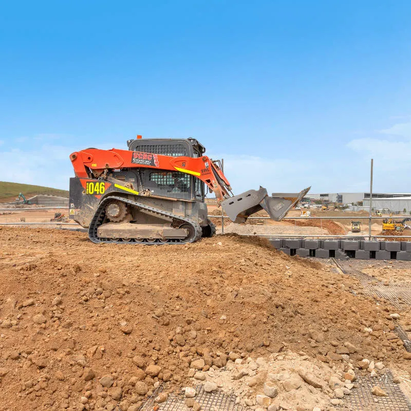 UCBC excavator and operator placing precast retaining wall units